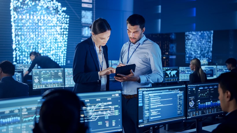 Group of tech workers using a tablet to control tech systems